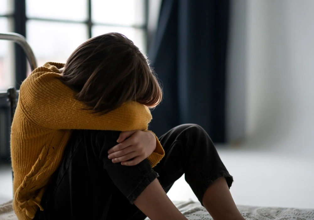 Barn sitter alene med hodet ned, symboliserer indre smerte – hvordan håndtere en depressiv episode i hverdagen.