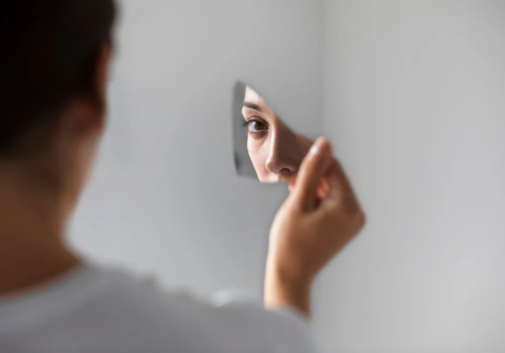 En person med obsessiv-kompulsiv personlighetsforstyrrelse som ser på sitt eget speilbilde i et knust speil, noe som symboliserer indre konflikt og perfeksjonistiske tendenser.
